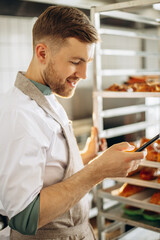 Man baker at the kitchen using phone