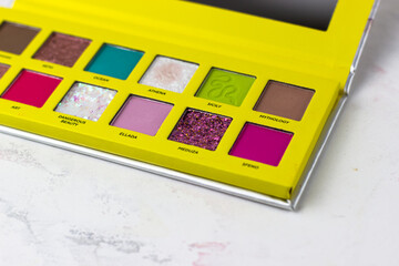 Eye shadow in a bright yellow case on a white background. Makeup Artist Cosmetics