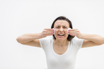 Photo of woman cleaning face with cosmetic sponges.