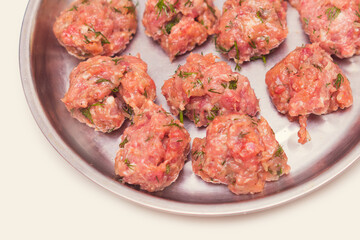 Prepared raw lumps of minced meat on a metal tray. Top view close up.