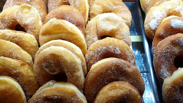 Donut-shaped breads with cream filling being displayed at a Brazilian bakery showcase.