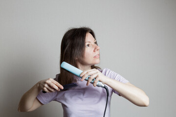 girl straightens her hair with a hair straightener.