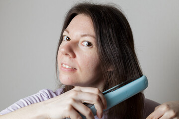 girl straightens her hair with a hair straightener.
