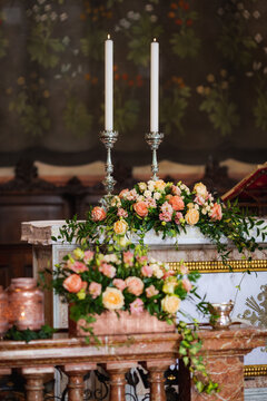 Wonderful bunch of roses on the altar of a church in front of two burning candles. Decoration for a wedding