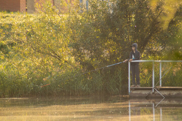 At dawn, a boy, in a tracksuit, is fishing on a pontoon. Banner, cover, flyer, layout design.
