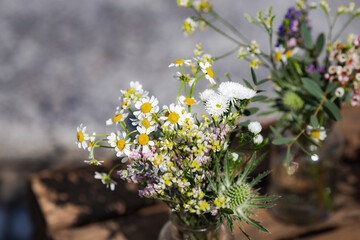Glass jars containing wildflowers in front of some wooden boxes used as decoration for a wedding 