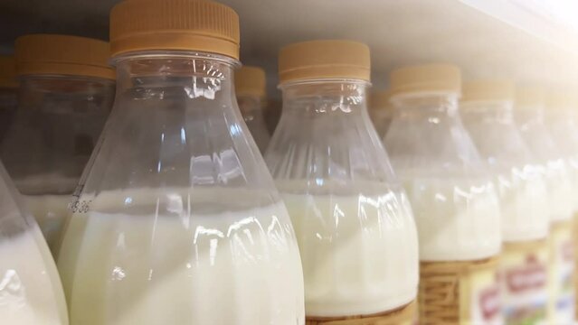Milk in bottles stands on the shelf of a supermarket or a grocery store. Close-up