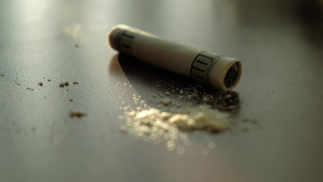 Rolled dollar bill against the background of heroin or cocaine powder, close-up