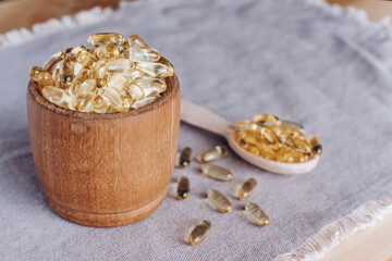 Fish oil capsules with omega-3 and vitamin D in spoon on linseed texture, concept of healthy eating, close up.