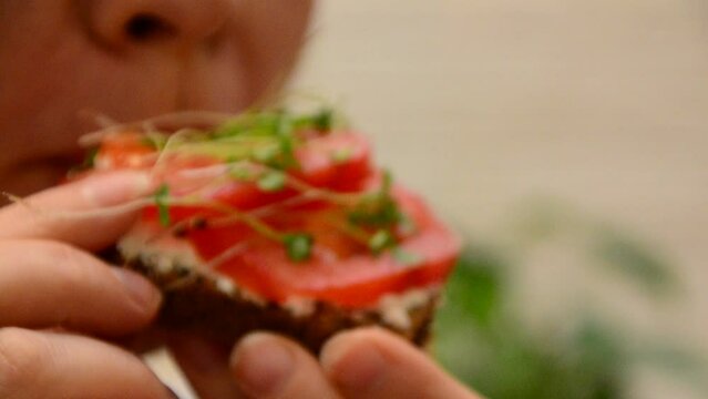 girl cooks and eats for breakfast open sandwich lettuce, tomato, soft cheese. Vegan sandwich with rye bread, spinach, microgreen isolated on white, top view. Healthy eating, diet sandwich closeup