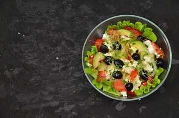 Fototapeta na wymiar Healthy salad in a bowl with olives, tomato, cheese, microgreens and avocado served for breakfast. healthy, delicious food with vitamins, vegetarian food, few calories. diet food