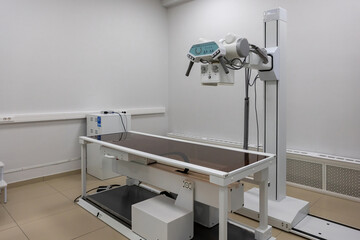 X-ray machine. An X-ray room with a scanning machine and an empty bed. Scanning of the chest, joints, lungs in the emergency room or hospital.