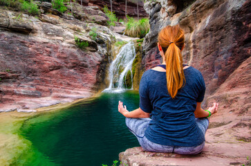 Girl meditating in a beautiful waterfall
