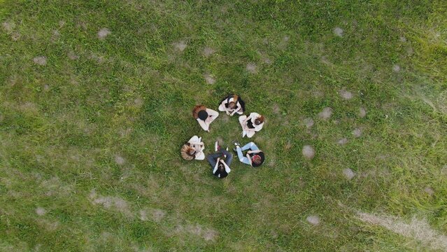 Six Girlfriends Are Sitting In A Circle On The Grass In The Park. Drone View.