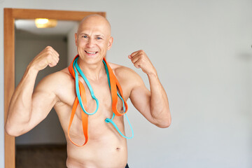 Handsome sports man doing shoulder lateral raise exercise with resistance band at home