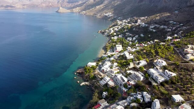 Aerial backwards reveal footage of Massouri village on Kalymnos island on sunny day. Aegean Sea, Greece.