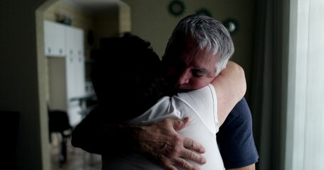 Older married couple embracing each other at home. Senior husband showing empathy and support with wife