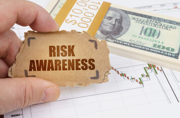 Against the background of dollars and a chart of quotations, a man holds a sign with the...
