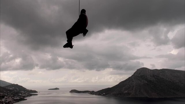 A climber (man) swings on a rope against a stormy sky. Kalymnos, Greece.
