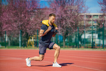Muscular young man exercising with heavy weight bag in the sport stadium. Sporty man working out with heavy weight bag.