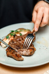 dish plate with meat steak on the bone in the restaurant. man cutting meat steak