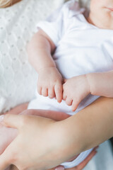 Young beautiful mother with blue eyes holds her little newborn daughter in her arms. Motherhood. Care. Baby.