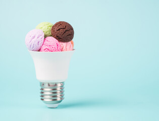 Ice cream scoops with various flavors in a lightbulb cone. High electricity costs minimal concept. - obrazy, fototapety, plakaty