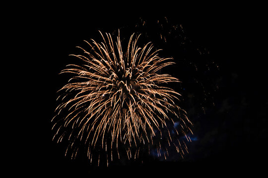 Firework over the ordinary European city at night near water, orange
