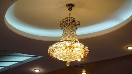 Luxurious crystal chandelier on the ceiling. Bottom view. Close-up. Huge crystal gold chandelier with candles.