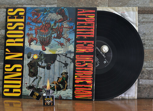 Album em vinil e isqueiro aceso da banda de rock famosa do estado unidos da am&eacute;rica, pousados em cima de um suporte de madeira velho