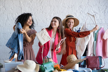 Obraz premium Happy women at swap party. Choose casual clothes, shoes, hats, bags, jewellery. Idea of exchange your old wardrobe for new. Eco friendly cloth concept. Zero waste shopping, reduce and reuse, donation