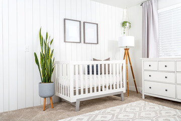 A modern farmhouse baby nursery bedroom with blank mock-up picture frames on the wall.  - obrazy, fototapety, plakaty