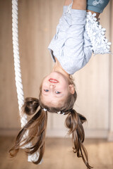 Fototapeta na wymiar girl is doing exercises, hanging on the rings upside down