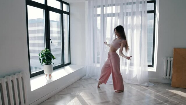 Street dancing - young slim woman dances in white studio