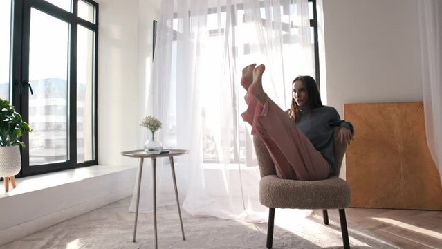 Modern dancing - a young woman dancing around a chair in a spacious room