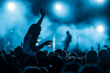Silhouette of a woman with raised hands on a concert