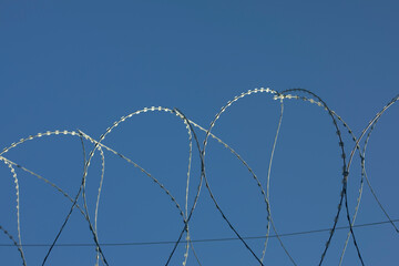 Barbed wire rings on fence. Protected area.