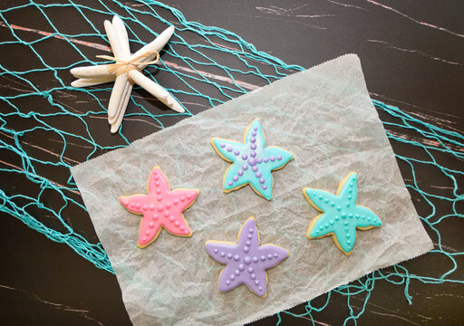 Star fish sugar cookies with royal icing on ocean theme background.