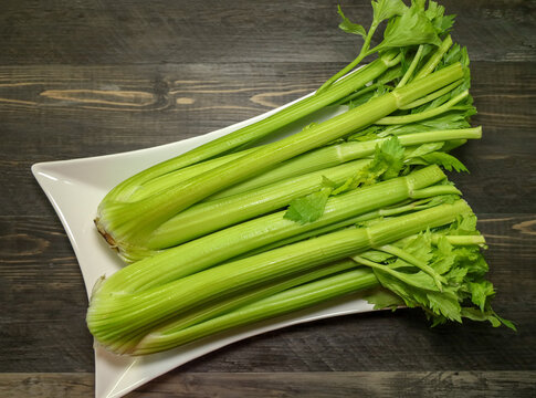 Top View Of Two Heads Of Celery On A White Platter.