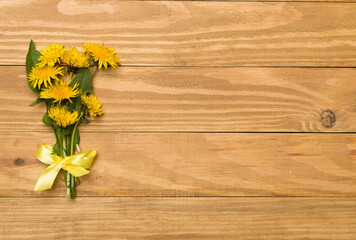 Yellow dandelion on wooden background, top view
