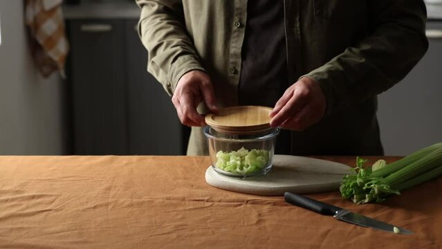 vegetarian man cuts Celery on a chalkboard in the kitchen with a knife