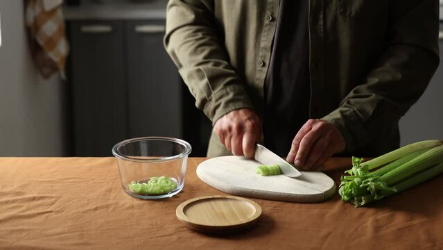 vegetarian man cuts Celery on a chalkboard in the kitchen with a knife