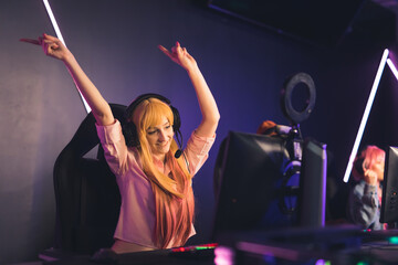 Fototapeta na wymiar young blonde Caucasian female gamer celebrating her success in online game medium shot cyber sport concept indoors. High quality photo