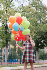 Teenage girl with colorful helium air balloons having fun outdoors. Tween Party. enjoying summer