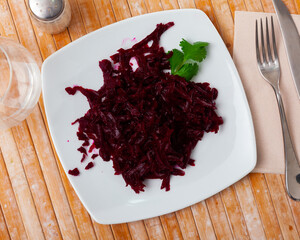 Traditional salad of Russian cuisine from boiled grated beetroot, decorated with a sprig of parsley