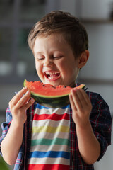 Little kid eating watermelon in kitchen