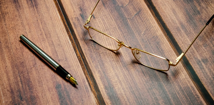 Top view glasses and pen on the wooden background