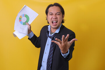 Angry boss screaming and showing a growth graph of bad report isolated on yellow background 