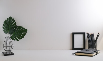 Home office desk with, stationery, picture frame and potted plant on white table. Copy space.