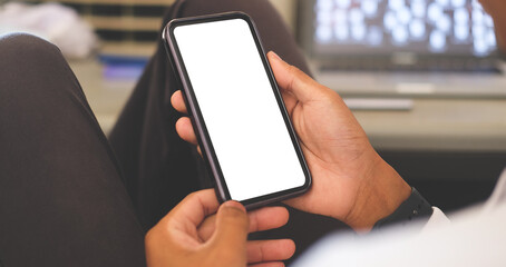 Over shoulder view of young man hands holding smart phone empty screen while sitting at workplace...